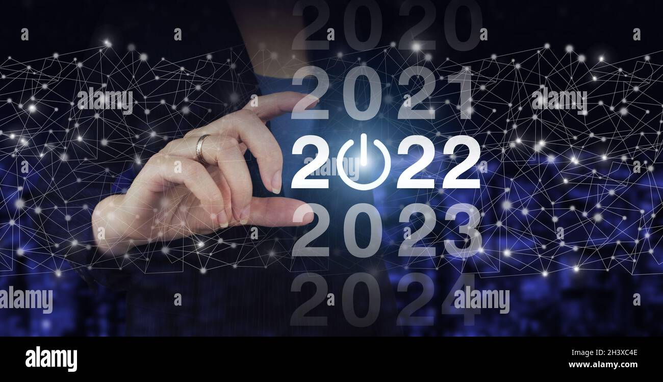 Benvenuto anno 2022. Business nuovo anno di concetto scheda. Mano Hold digitale ologramma 2022 segno sulla città scuro sfondo sfocato. Concept inizio nuovo anno 2022 Foto Stock