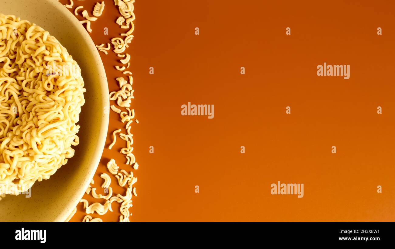 Spaghetti secchi crudi in un recipiente per zuppa beige in ceramica su fondo marrone. Pasta, per la preparazione della quale è smoug Foto Stock