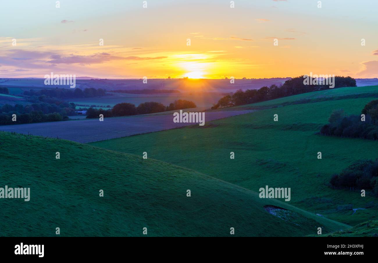 Ultimi momenti di un tramonto dorato, nuvola minimale all'orizzonte su una valle verde erba profonda, Pewsey vale, North Wessex Downs AONB UK Foto Stock