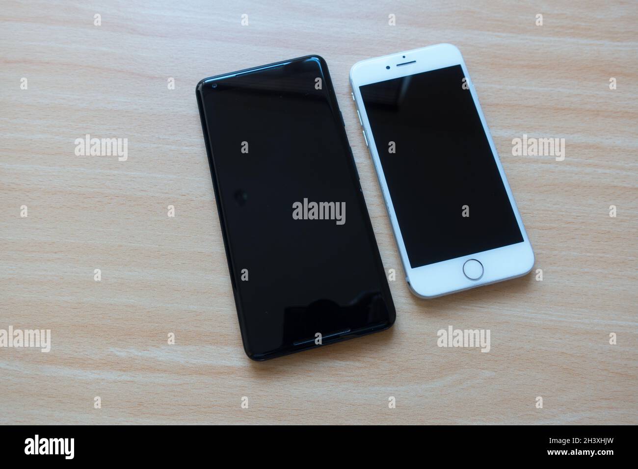 Smartphone Android e Apple posizionati uno accanto all'altro su un tavolo Foto Stock