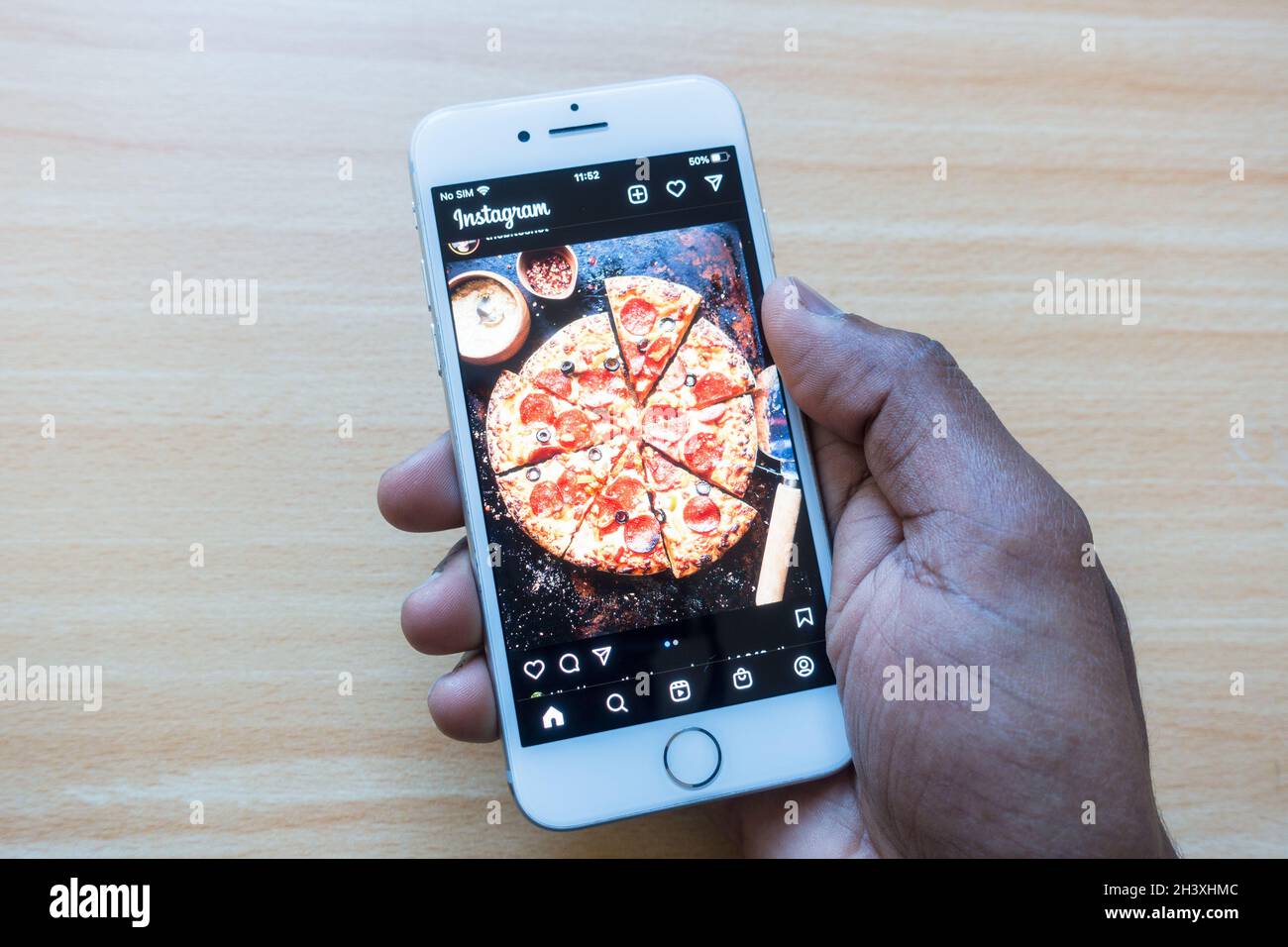 Persona maschio adulta che guarda una fotografia Pizza su Instagram utilizzando il telefono cellulare Apple Foto Stock
