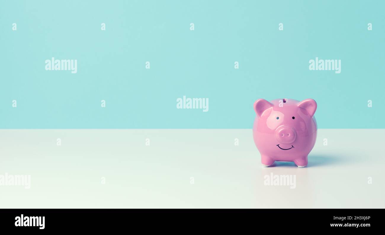 Banco di maialino rosa in ceramica su sfondo blu. Concetto di aumento del reddito da conti bancari Foto Stock