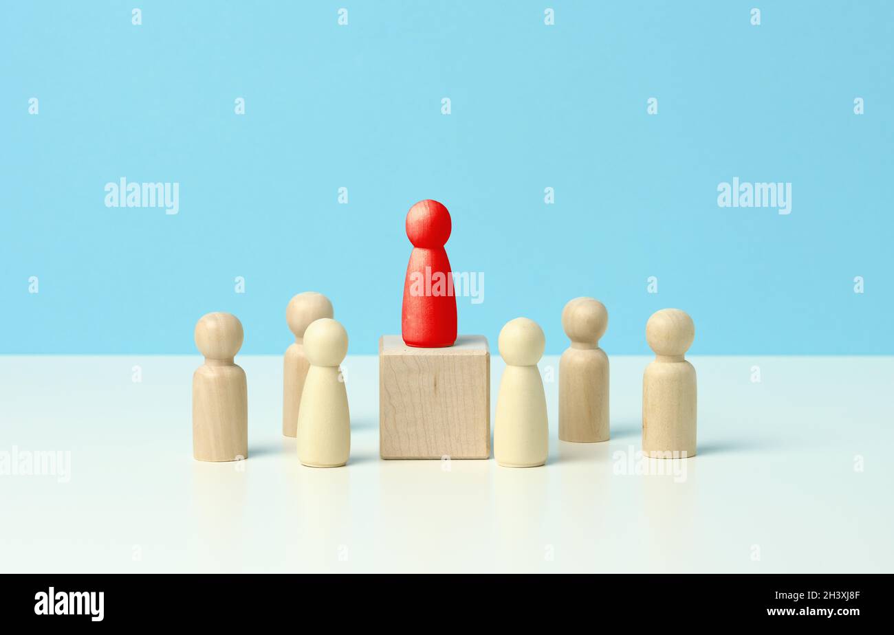 Figurine di legno di uomini su sfondo blu. Concetto, leadership e discussione di lingua pubblica. Foto Stock