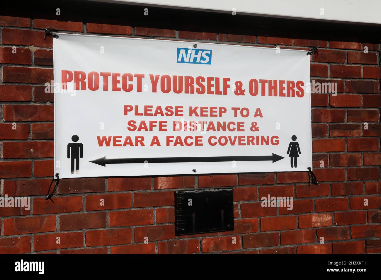 Un segnale di distanza di sicurezza NHS Covid su un muro in Sussex, Regno Unito. Foto Stock