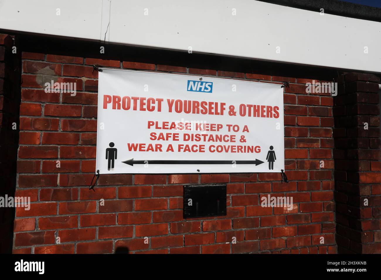 Un segnale di distanza di sicurezza NHS Covid su un muro in Sussex, Regno Unito. Foto Stock