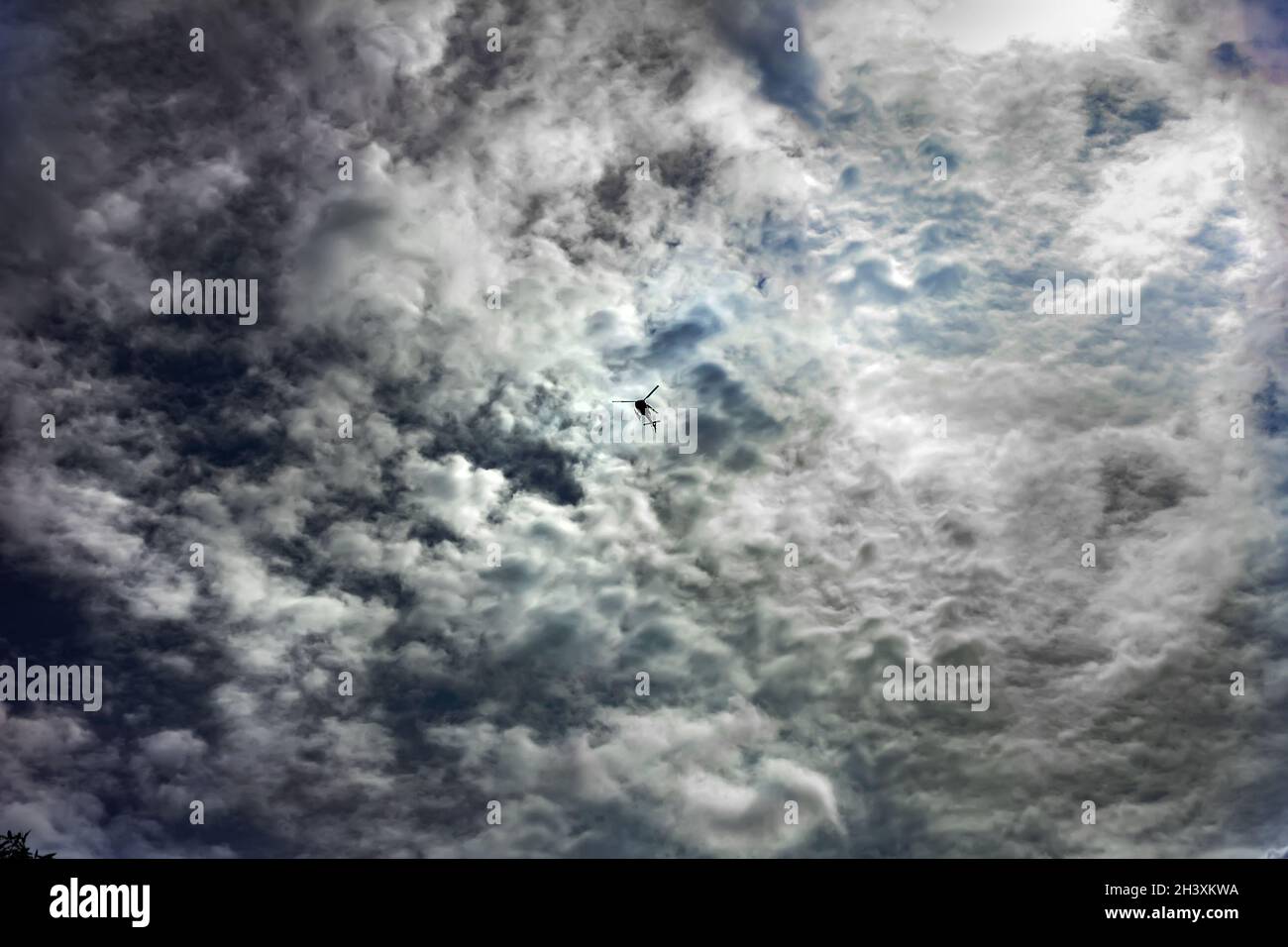 Elicottero piccolo e coraggioso in un cielo nuvoloso e profondo Foto Stock