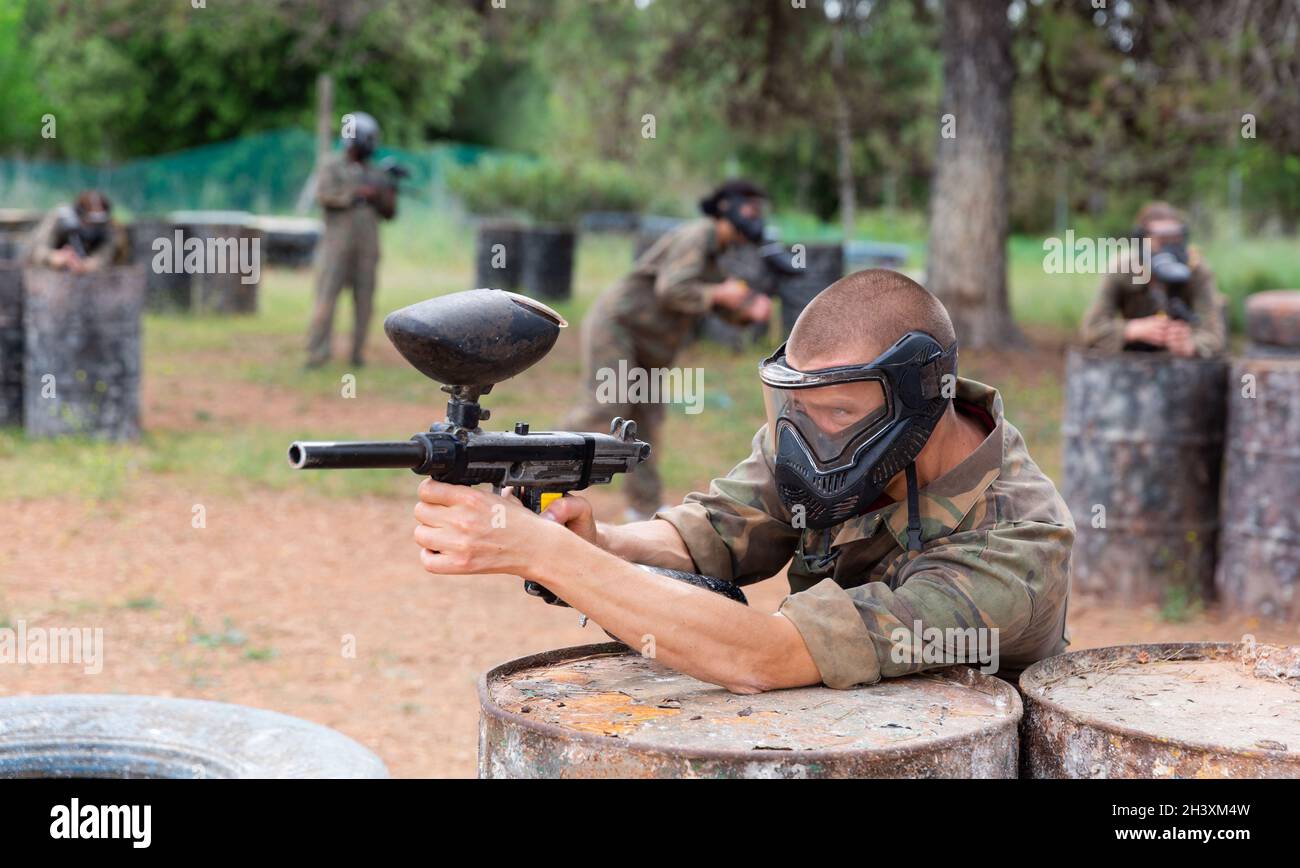 Paintball giocatore in camouflage e maschera mirante con pistola in sparo Foto Stock