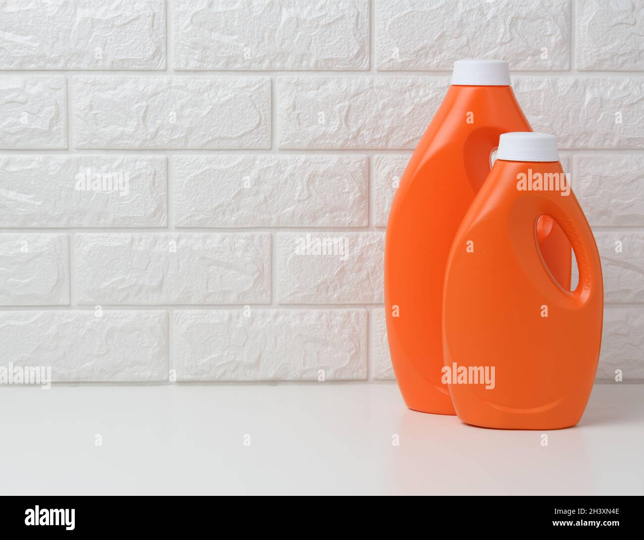 Bottiglia di plastica arancione per detersivo liquido per bucato su sfondo bianco Foto Stock