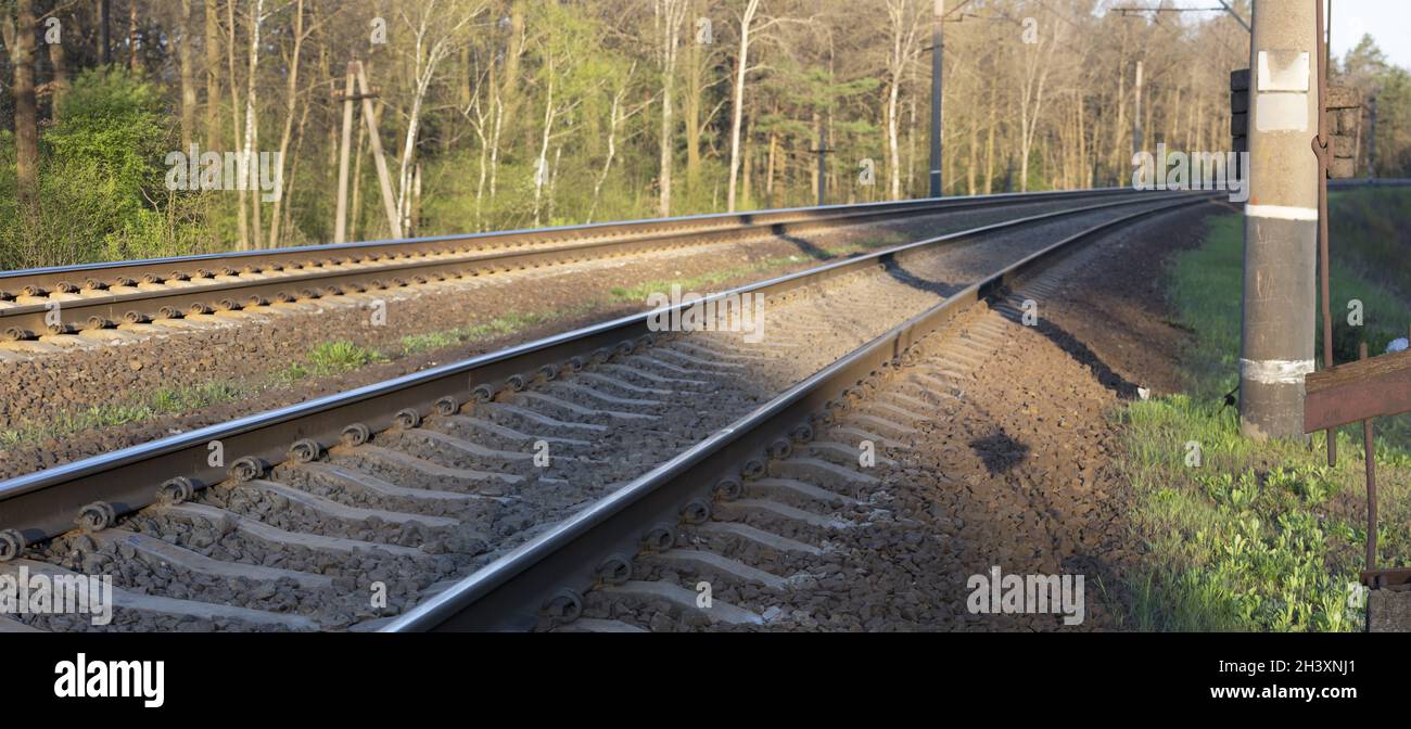 Panorama di due binari ferroviari a un giro attraverso la foresta. La strada su cui si muovono i treni, viaggia in treno. Foto Stock