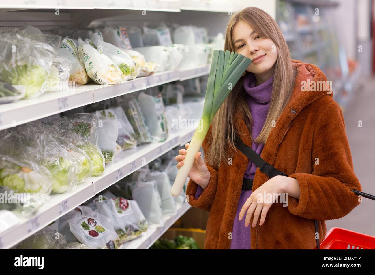 La giovane donna con un cestino di alimentari sceglie i prodotti nel reparto verdure. Foto Stock