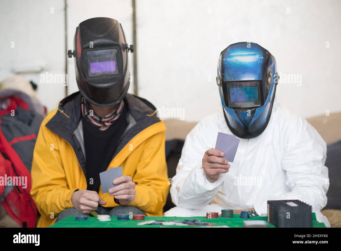 Due saldatori in maschere di saldatura giocare a poker. Foto Stock