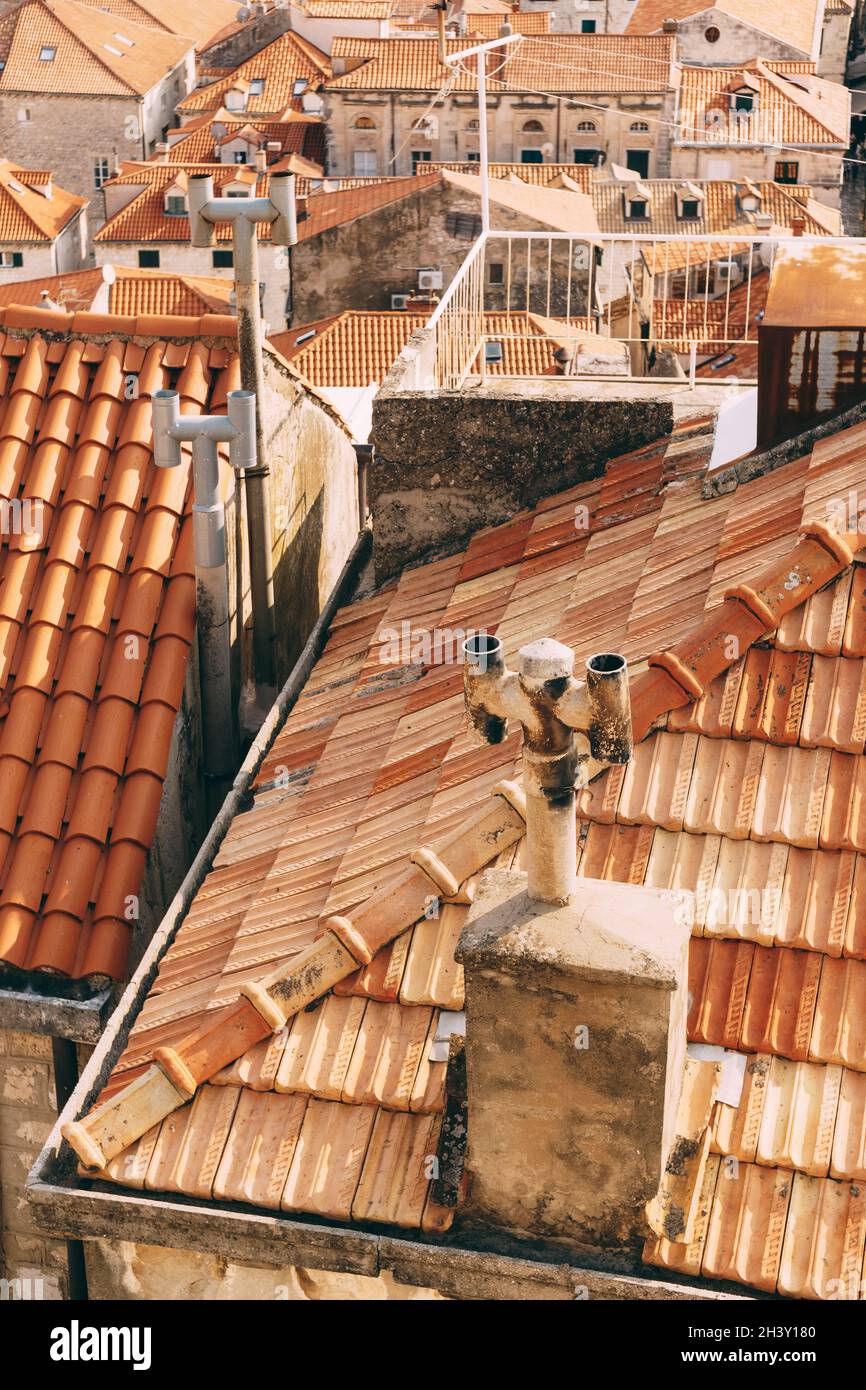 Vecchi tetti arancioni con camini arrugginiti e un balcone sul tetto. Foto Stock