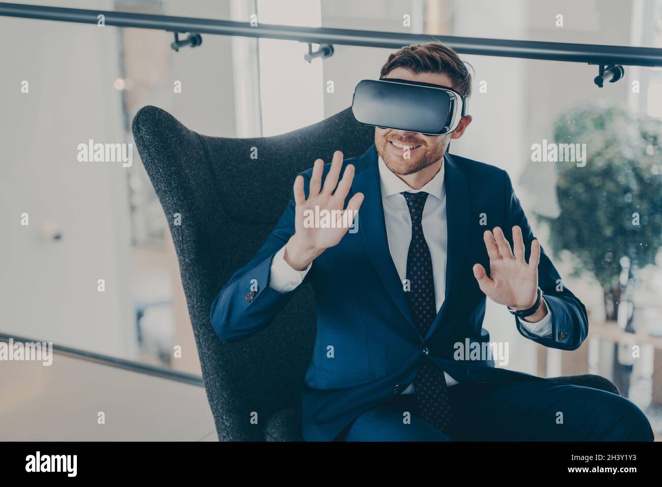 Impiegato seduto nella hall del centro finanziario dell'azienda con occhiali per visore VR Foto Stock