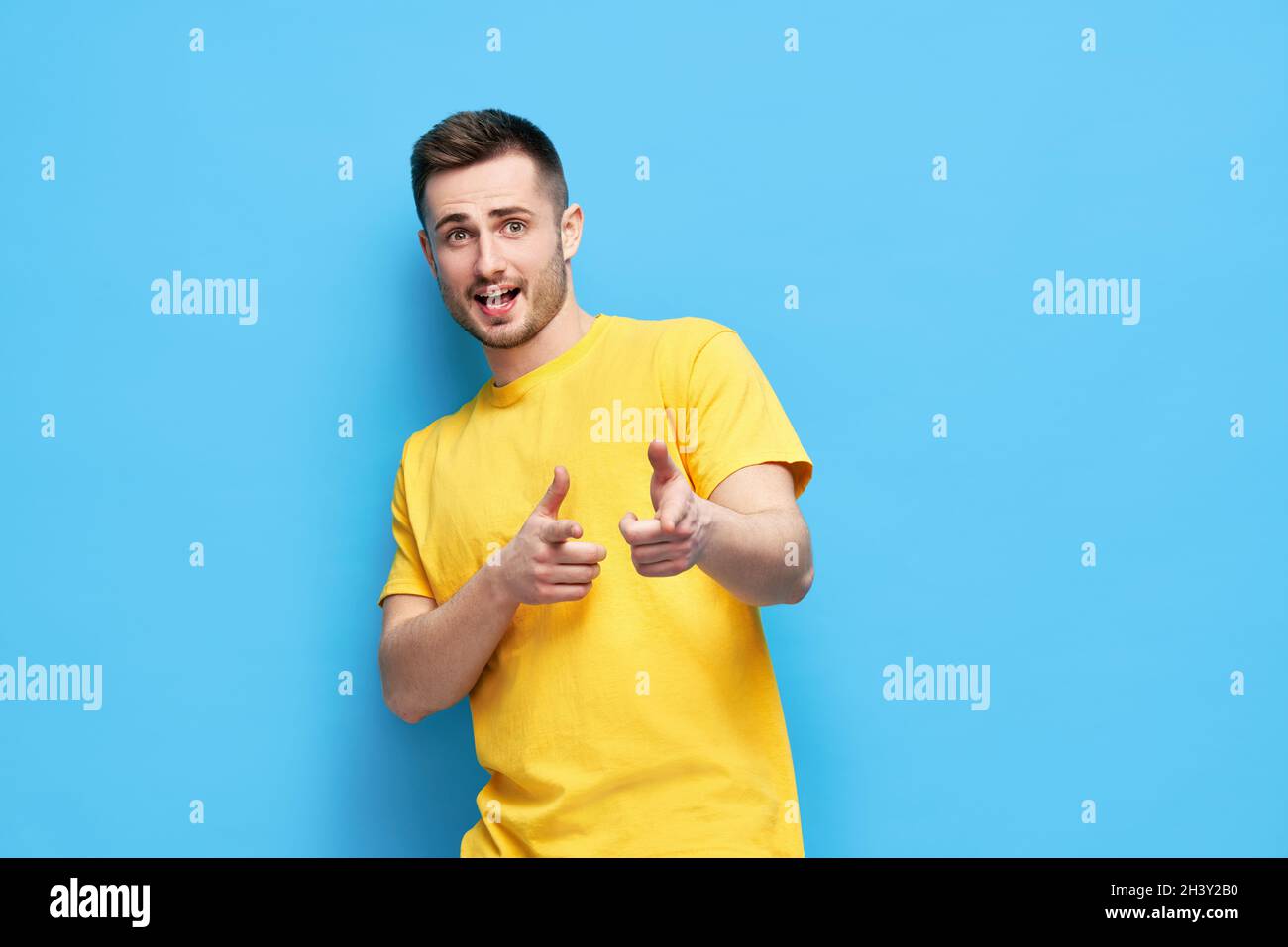 Divertente uomo gioioso che ti indica e guarda la fotocamera su sfondo blu Foto Stock