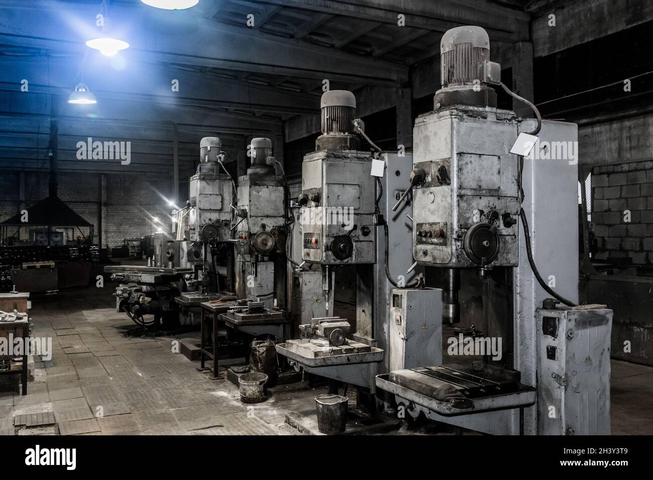 Vecchie fresatrici verticali con motori elettrici flangiati per la lavorazione dei metalli nell'officina dell'impianto industriale. Foto Stock