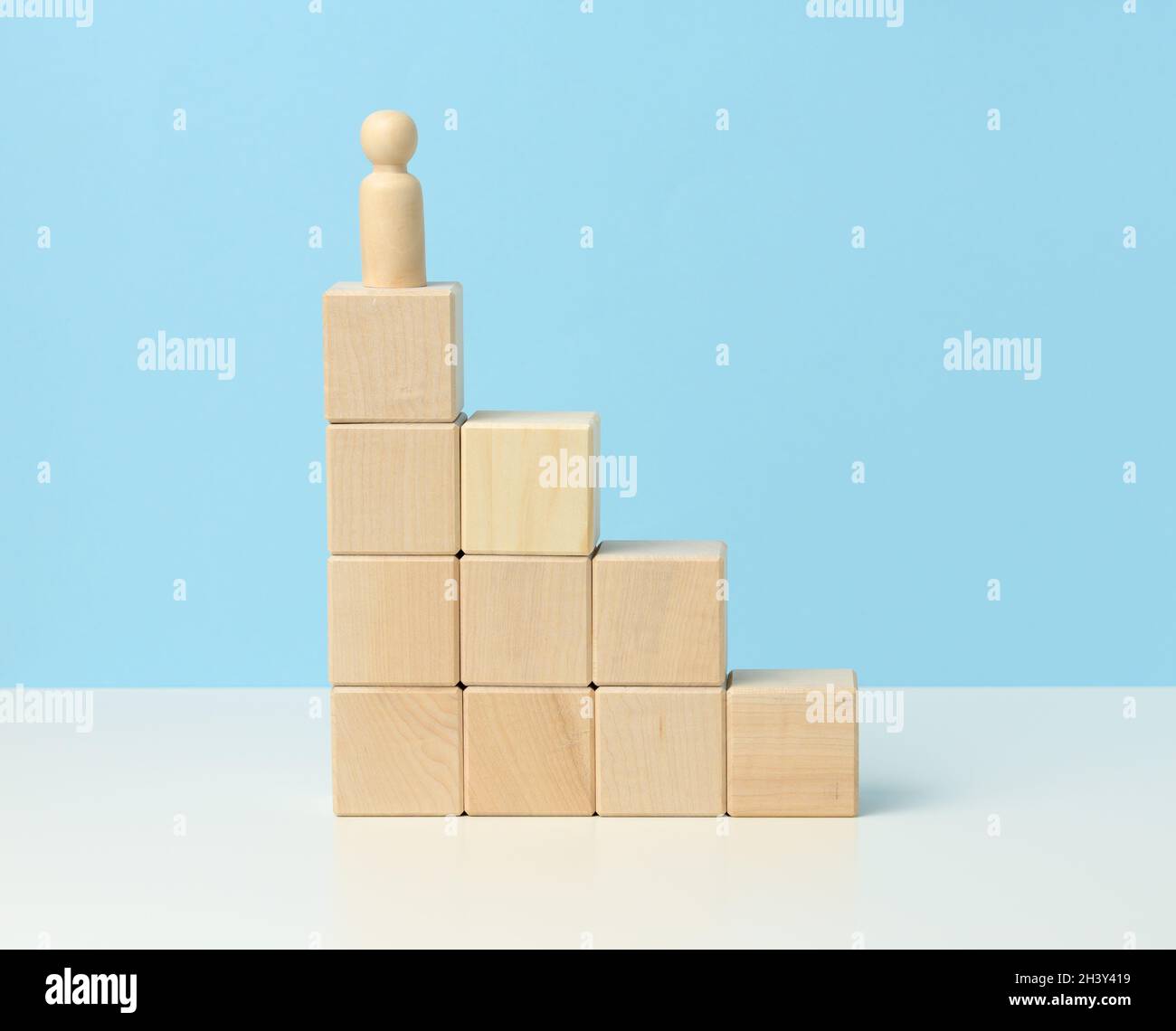 Figurine di legno di un uomo sulla parte superiore di cubi di legno. Il concetto di volutamente, raggiungimento di obiettivi, superamento di ostacoli Foto Stock