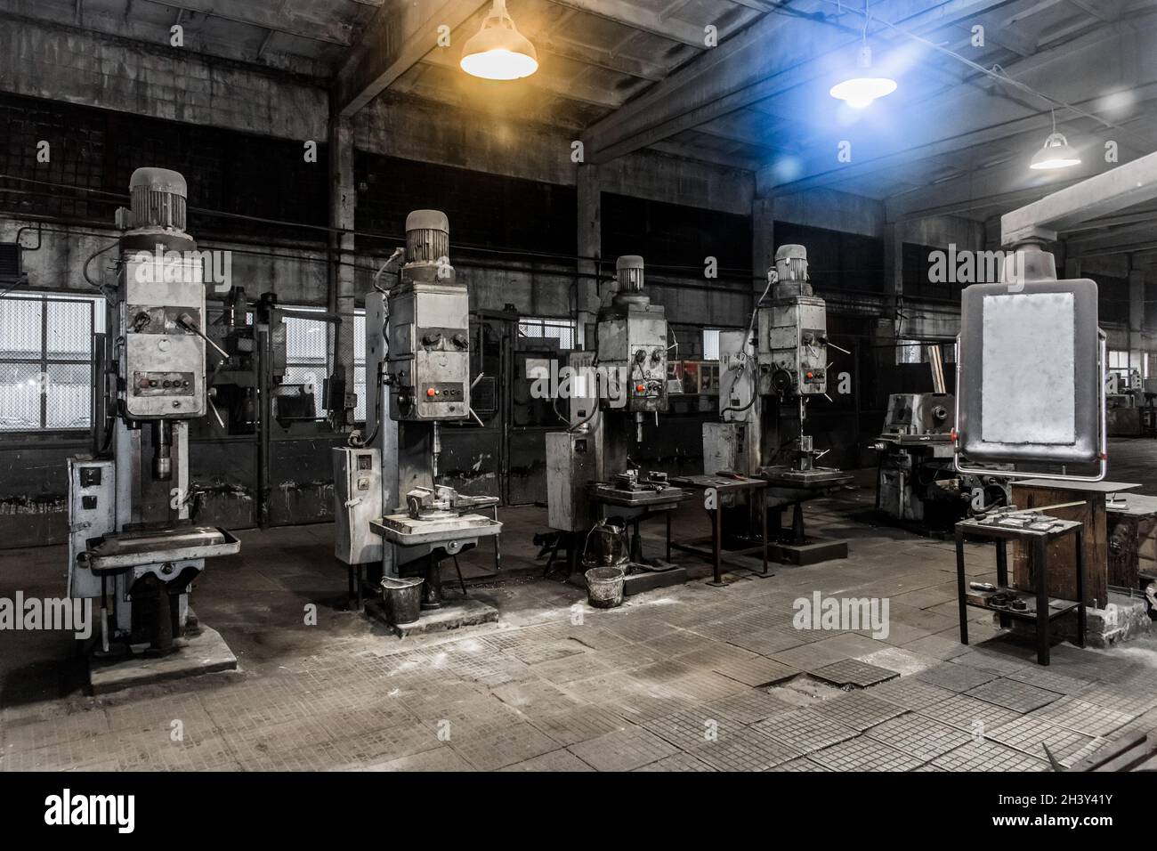 Vecchie fresatrici verticali con motori elettrici flangiati per la lavorazione dei metalli nell'officina dell'impianto industriale. Foto Stock