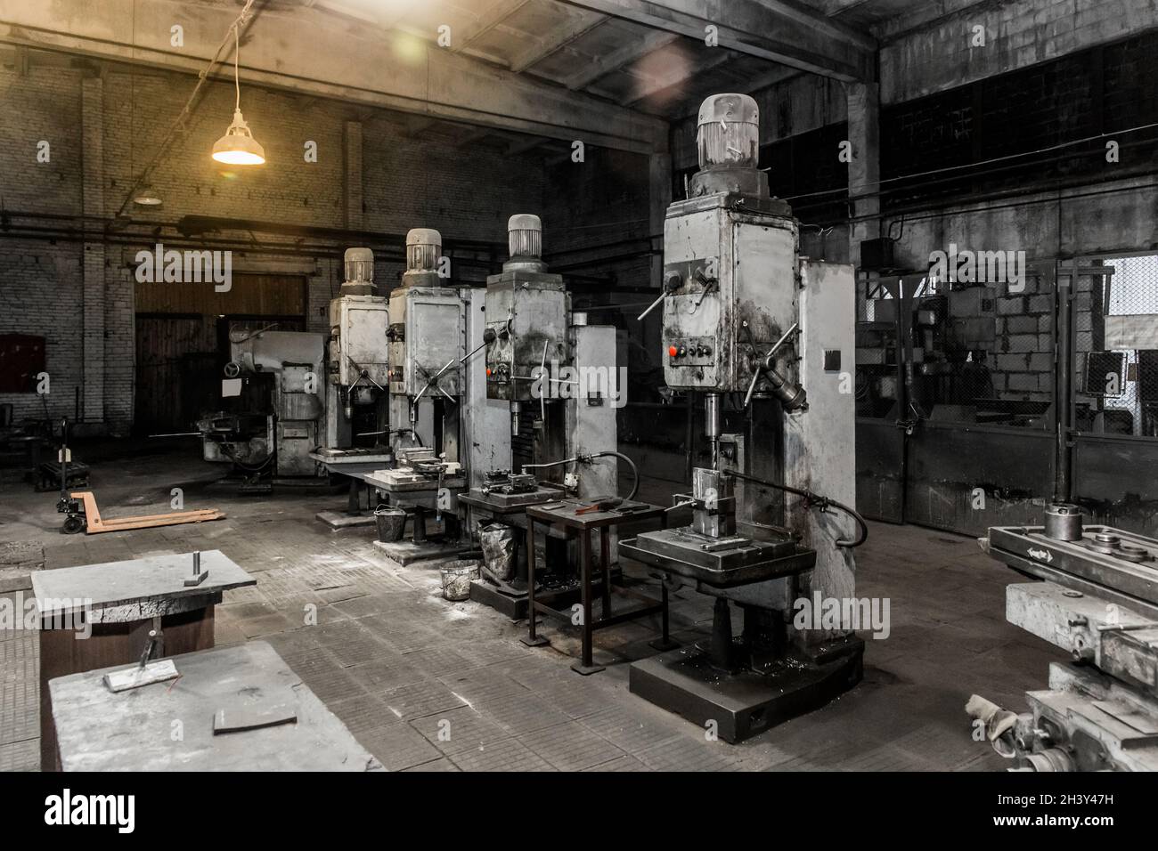 Vecchie fresatrici verticali con motori elettrici flangiati per la lavorazione dei metalli nell'officina dell'impianto industriale. Foto Stock