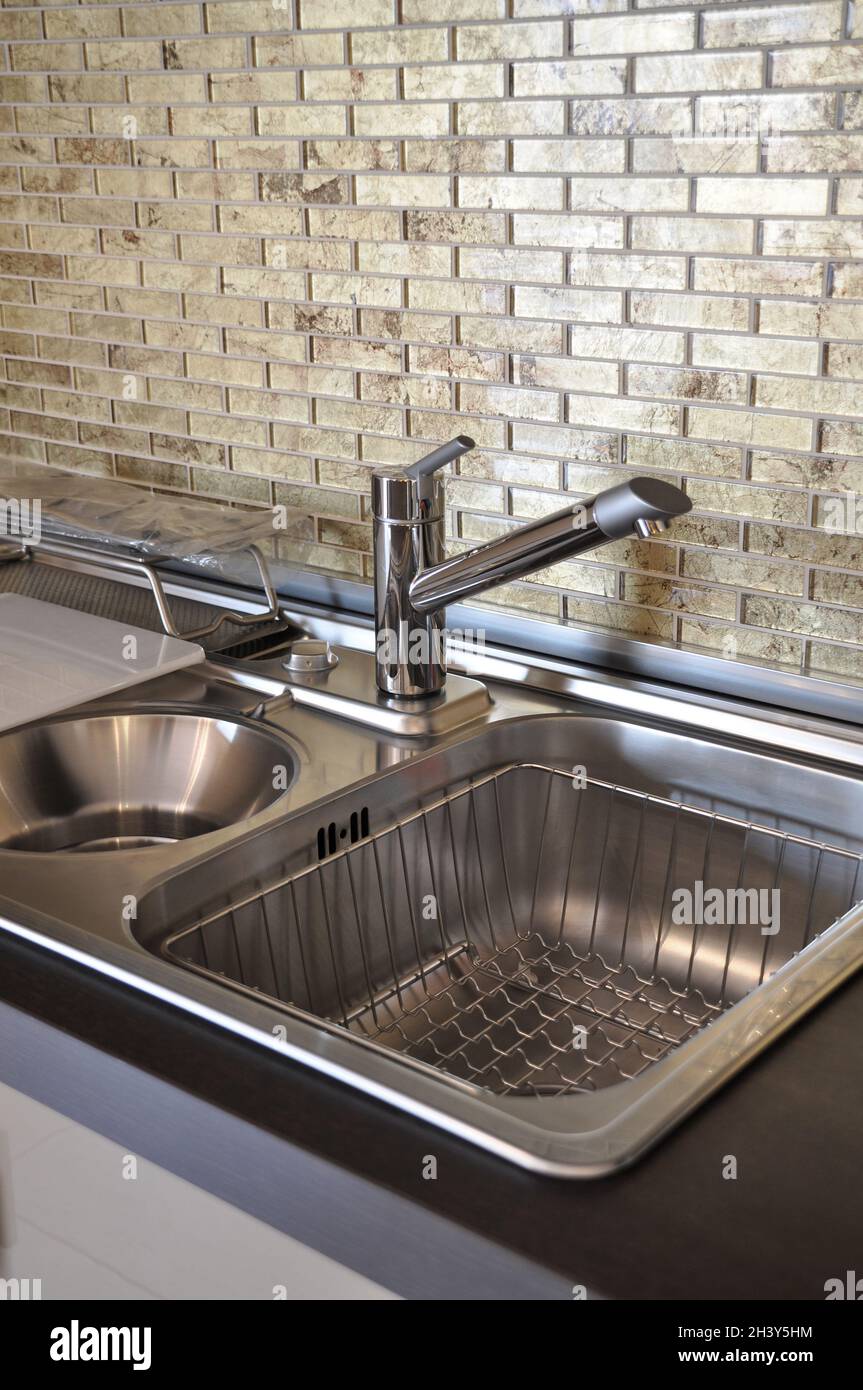 Interno di lussuosa cucina moderna e lavandino, rubinetto e scarico in acciaio inossidabile Foto Stock