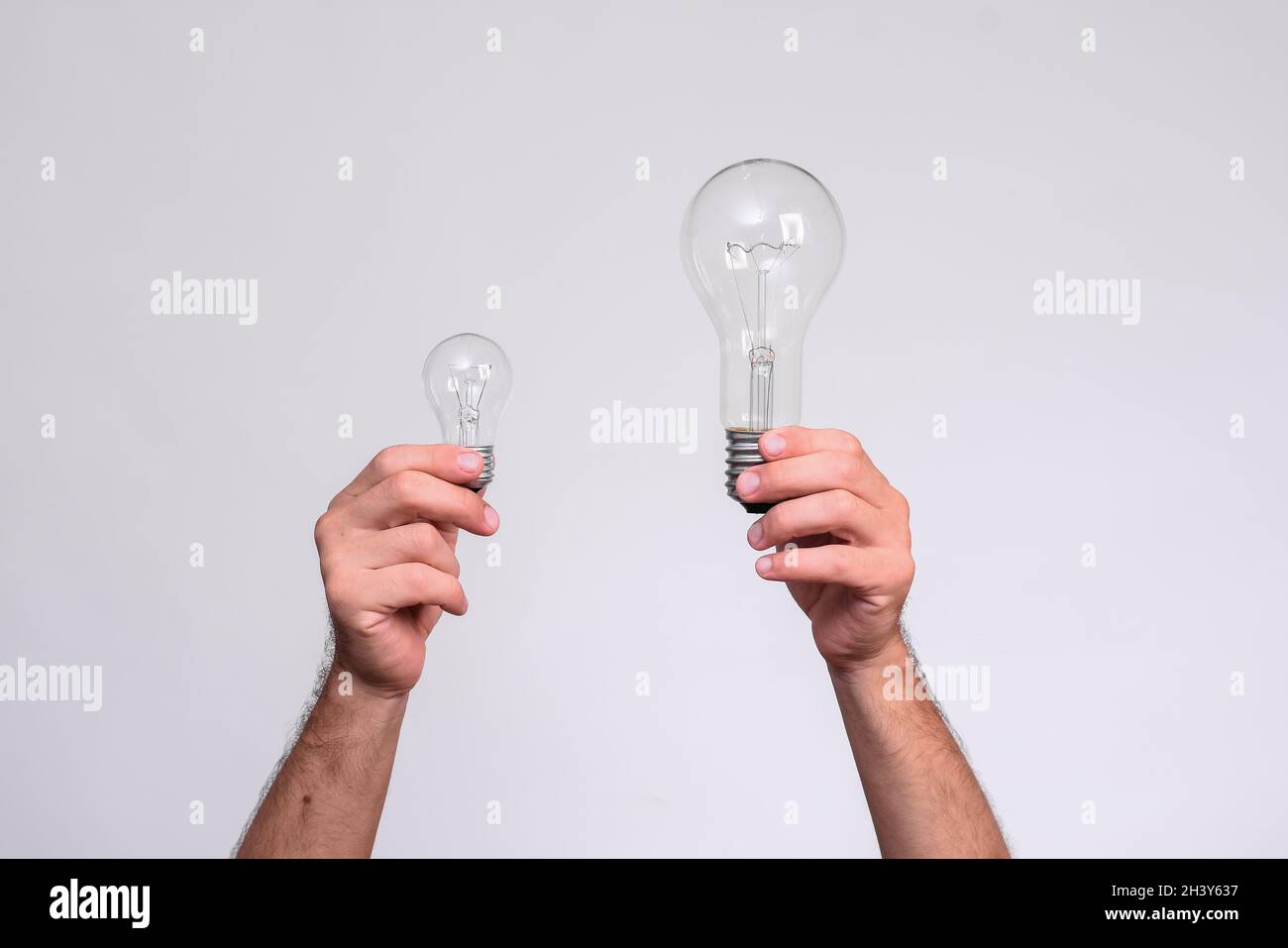 Due lampadine nelle mani degli uomini, grandi e piccole lampade ad incandescenza. Foto Stock