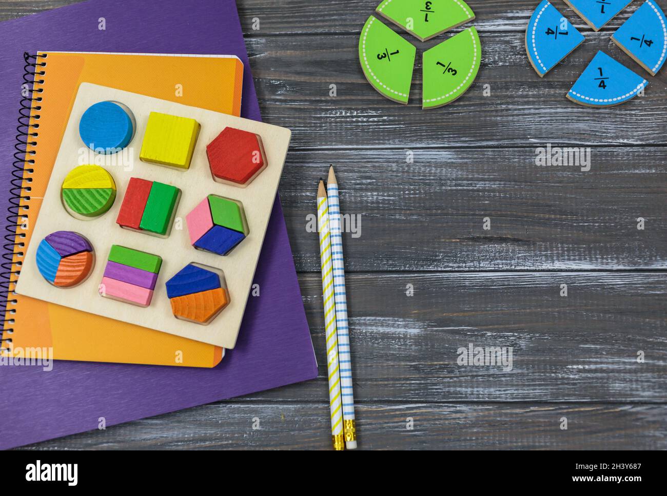 Frazioni multicolore, blocchi, taccuino su un tavolo di legno grigio. Ritorno a scuola, matematica divertente, giochi per l'asilo, istruzione prescolare. Foto Stock