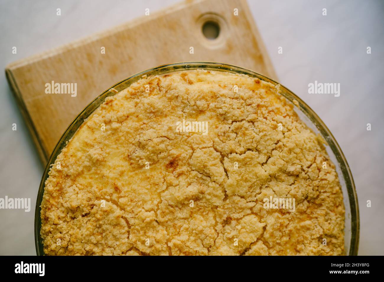 Torta crumble in stile ungherese con sensazione di cheesecake in una ciotola in vetro resistente al fuoco su un pannello di legno Foto Stock