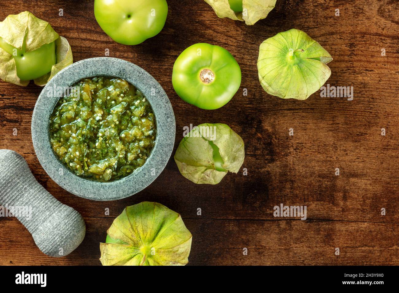 Tomatillos, pomodori verdi, con salsa verde, salsa verde, in una molcajete Foto Stock