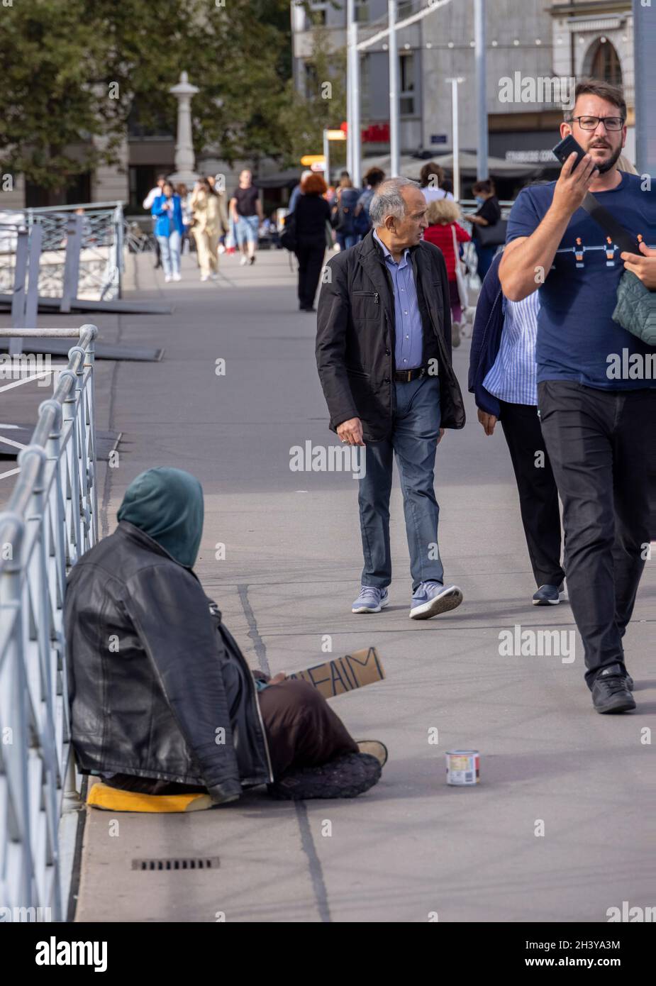 Pedoni passavano donna mendicante su Pont de la Machine, Ginevra, Svizzera Foto Stock