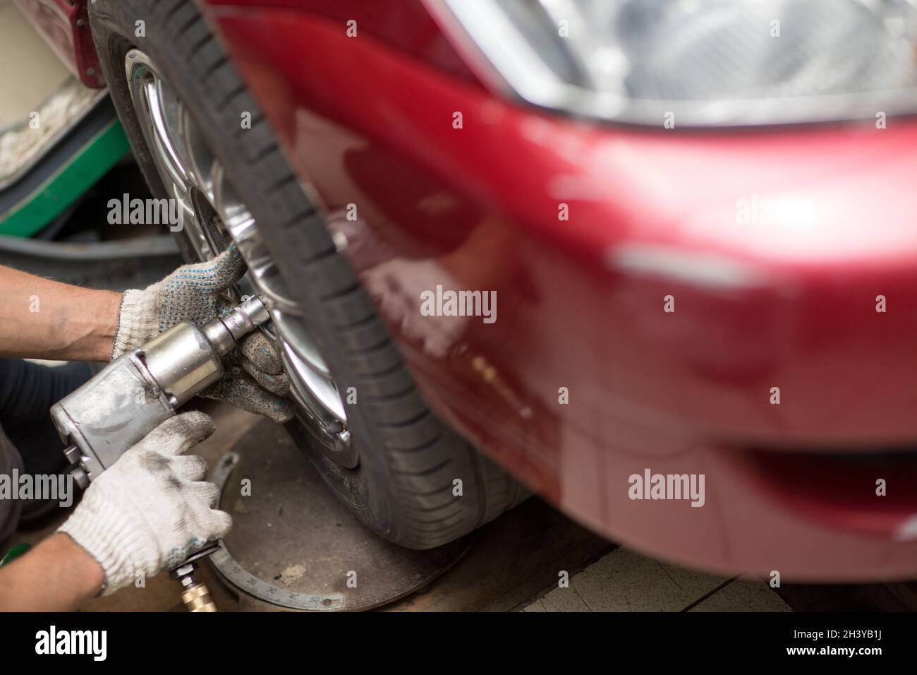 Riparare o sostituire la ruota di avvitamento meccanica della vettura presso la stazione di servizio di riparazione Foto Stock