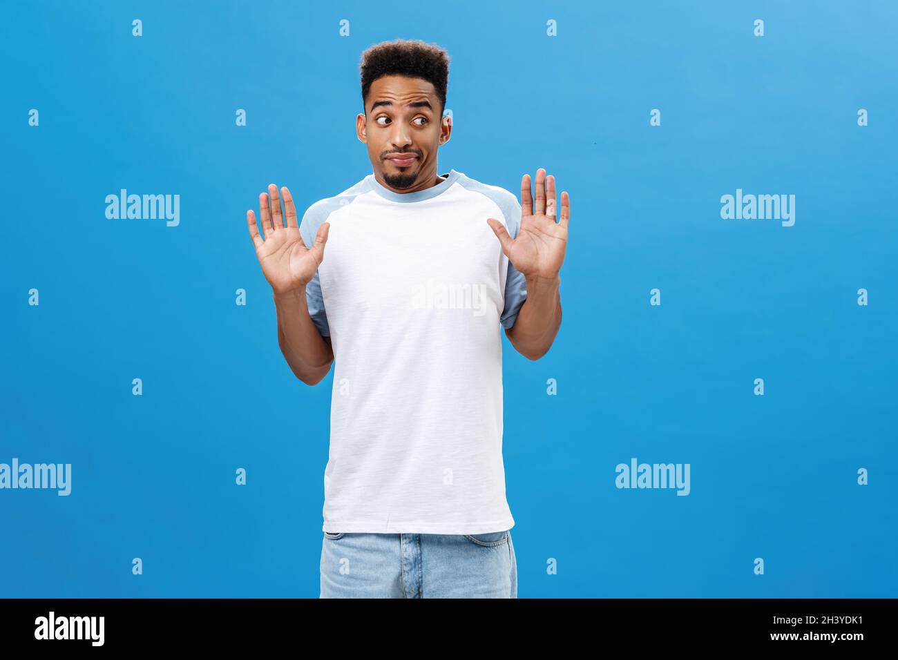 L'uomo che dice alla polizia non era lui. Unimpliced senza indizio intenso africano americano maschio con barba in casual vestito che alza palme i Foto Stock