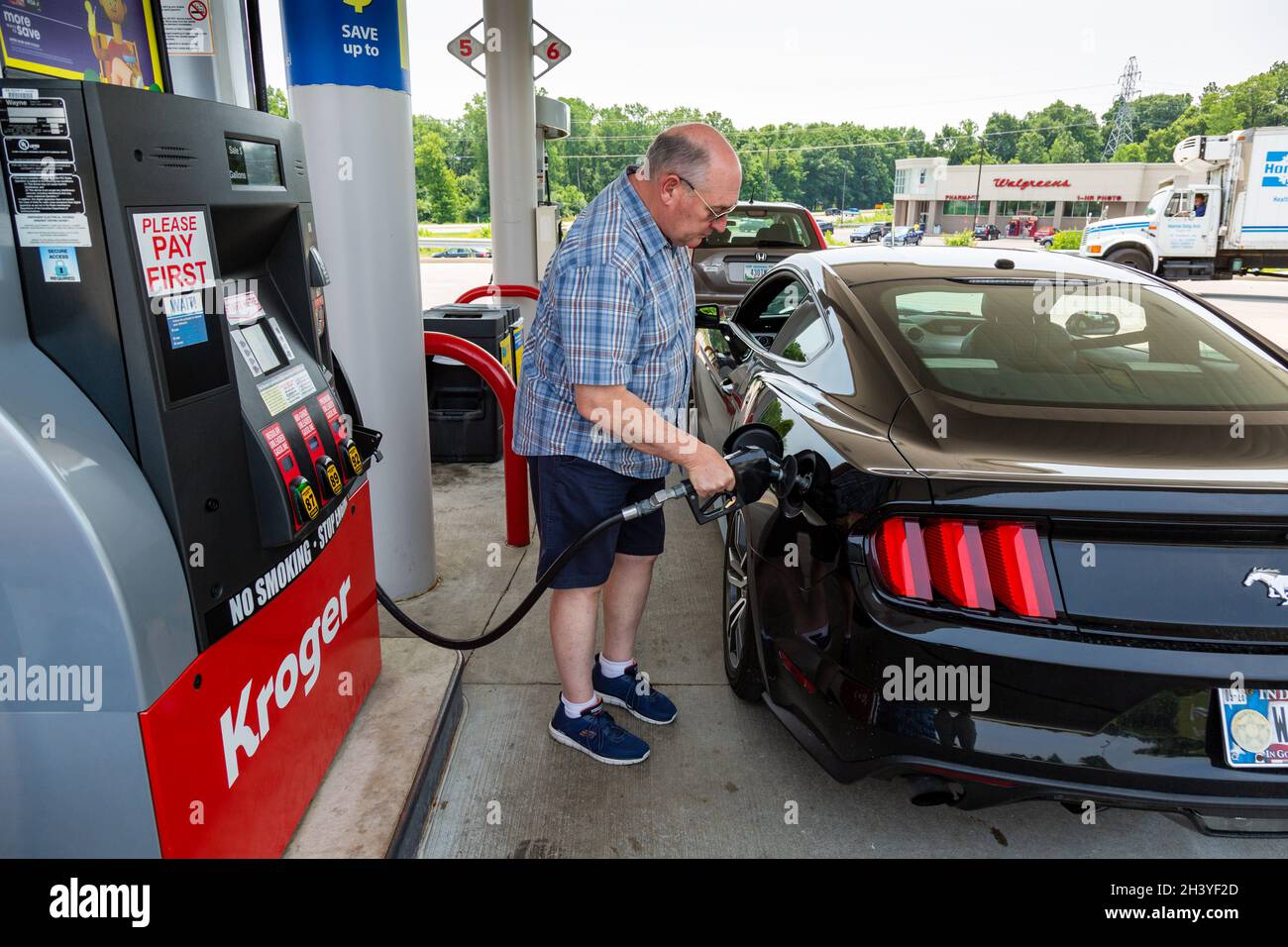 Un uomo pompa benzina in un nero 2015 Ford Mustang Fastback coupé in una stazione di servizio Kroger a Fort Wayne, Indiana, USA. Foto Stock