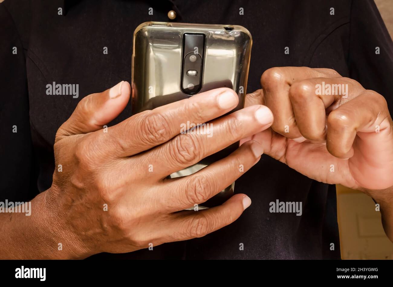 Mani di una donna giamaicana che è più di cinquantacinque in possesso Di Un telefono cellulare Foto Stock