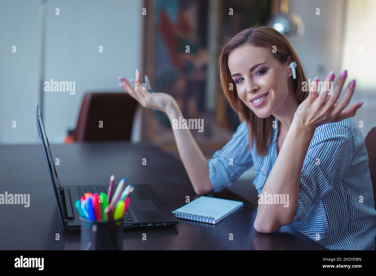Donna d'affari di successo con dispositivo a mani libere che mostra soddisfazione in ufficio domestico Foto Stock