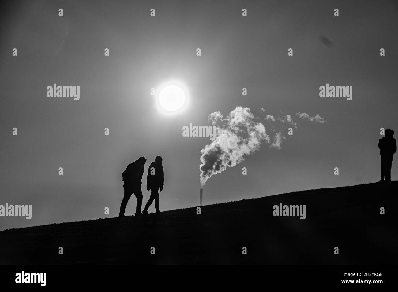 Riscaldamento globale: Un caldo sole e vapore si alza come le silhouette della gente si levano su una collina in Melbourne Australia . Foto Stock