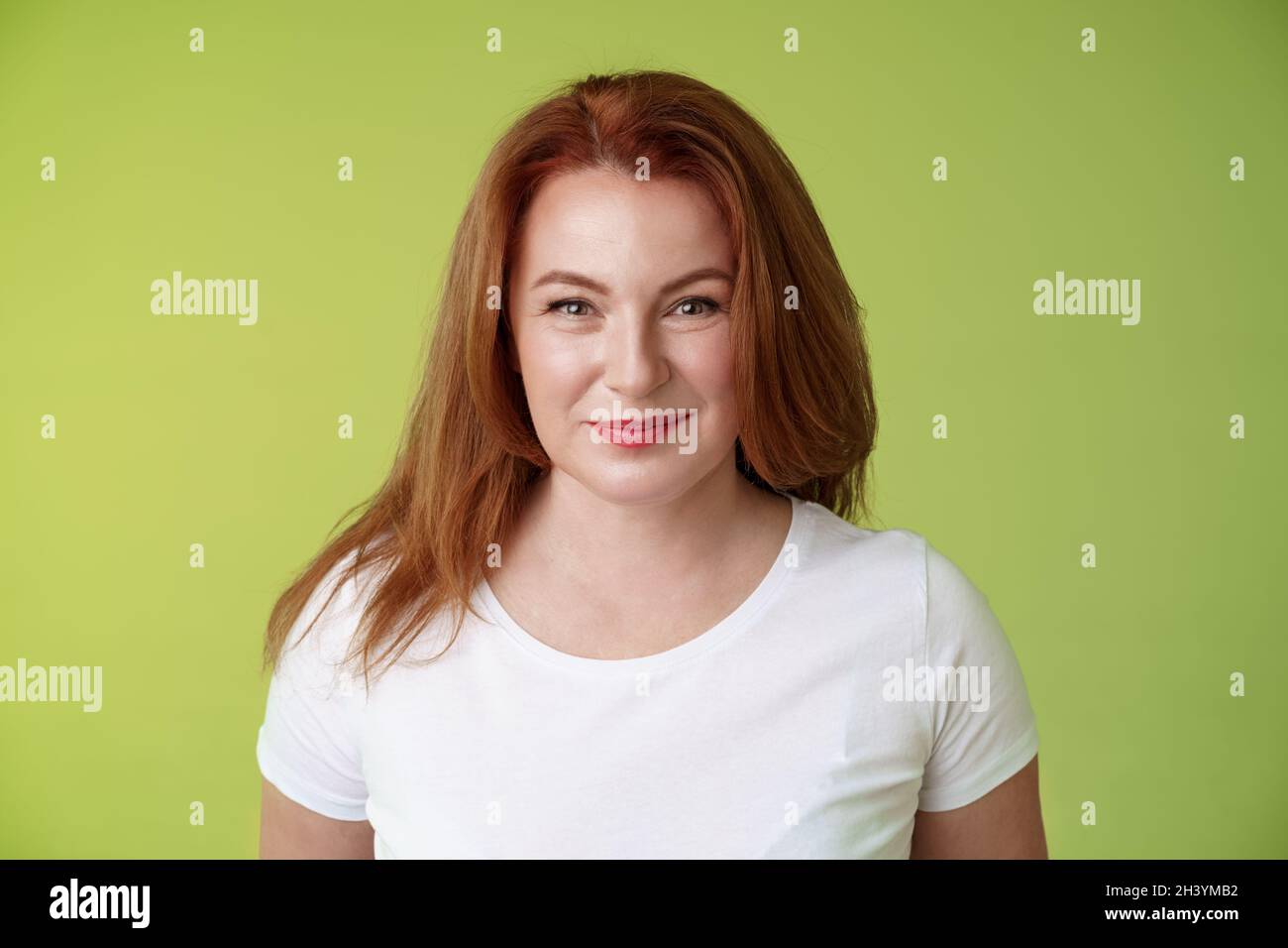 Appassionante sorridente rossa mezza età donna che grinning gioiosamente seducente motivato sguardo fotocamera determinato raggiungere obiettivo watc felice Foto Stock