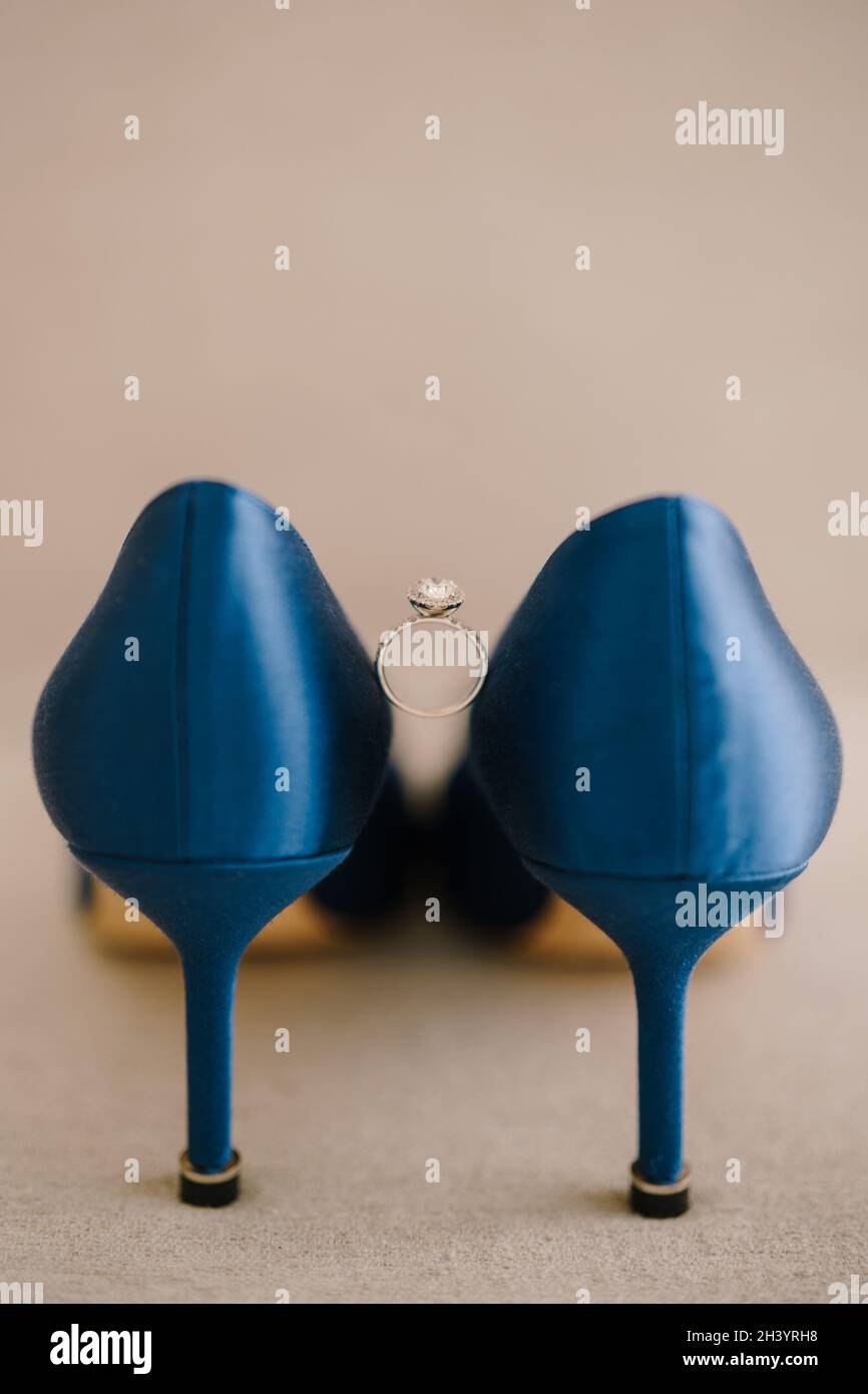 Anello di fidanzamento con una gemma tra scarpe blu con tacco alto sul  pavimento su sfondo beige Foto stock - Alamy