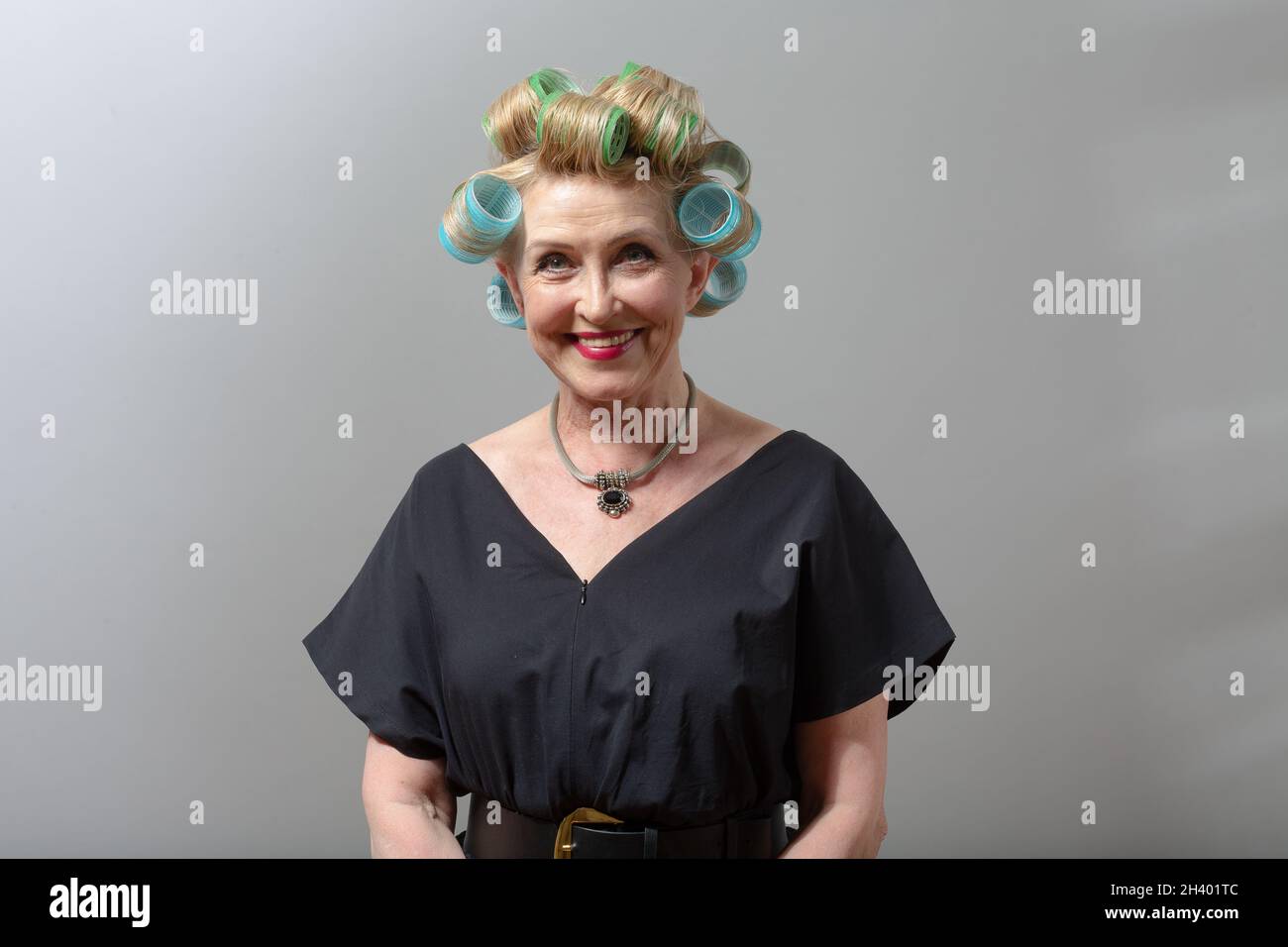 Donna anziana casalinga anziana con rulli arricciatori sulla testa dei capelli Foto Stock