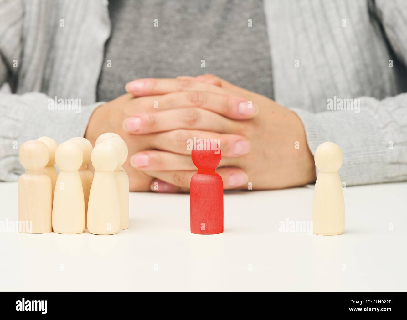 Gruppo di figure in legno, e uno in piedi. Tra loro c'è una figurina di legno rosso dell'uomo negoziatore. Trovare un compromesso, di Foto Stock
