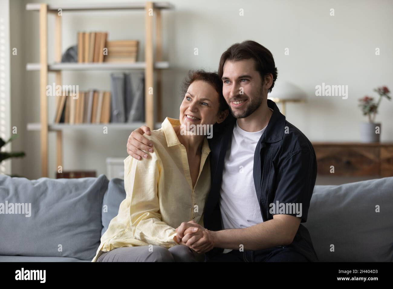 Sognante legame famiglia generazioni diverse poggiando su un comodo divano. Foto Stock