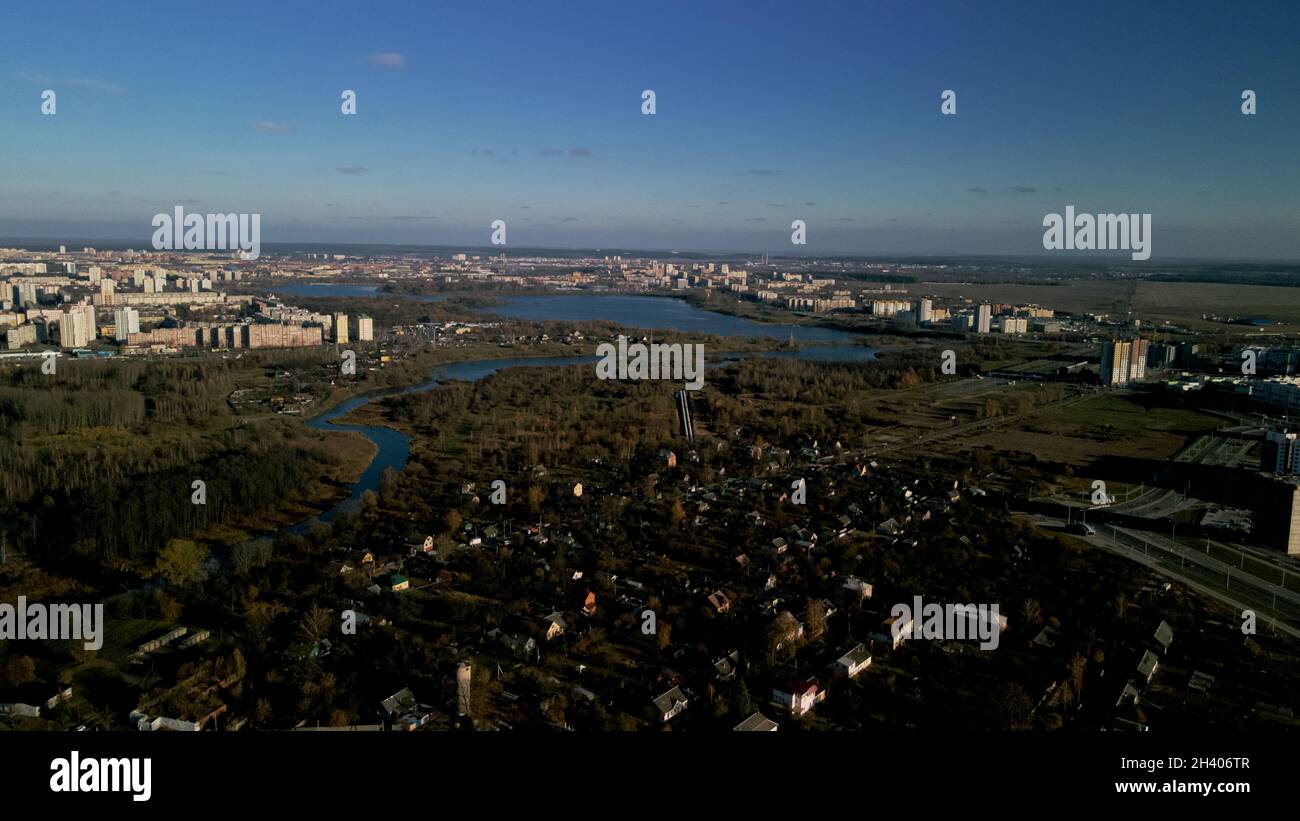 Parco autunnale della città con un fiume. Volare nei sobborghi. All'orizzonte si trovano alti edifici. Fotografia aerea. Foto Stock