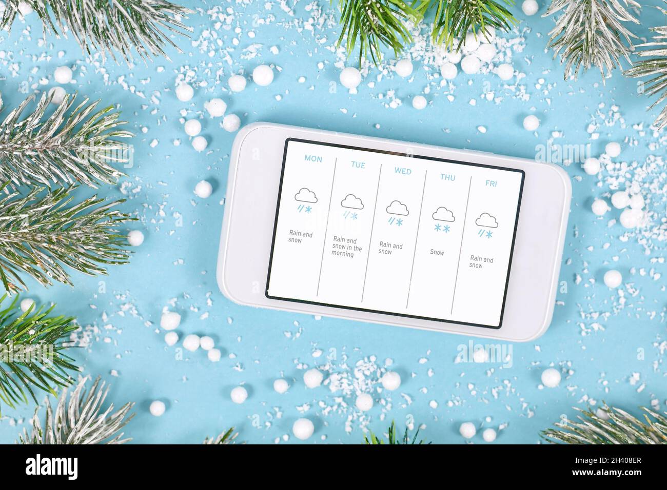 Concetto per temperature invernali fredde con neve che mostra il telefono cellulare con previsioni del tempo Foto Stock