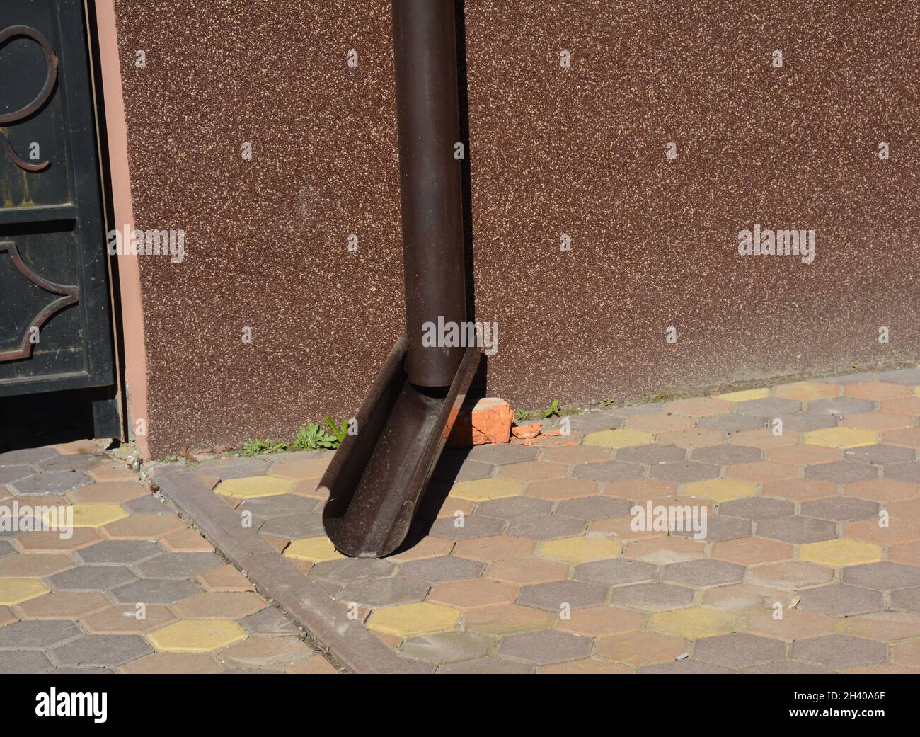 Tubo di scarico del gocciolatoio del tetto vicino alla parete di fondazione della casa Foto Stock