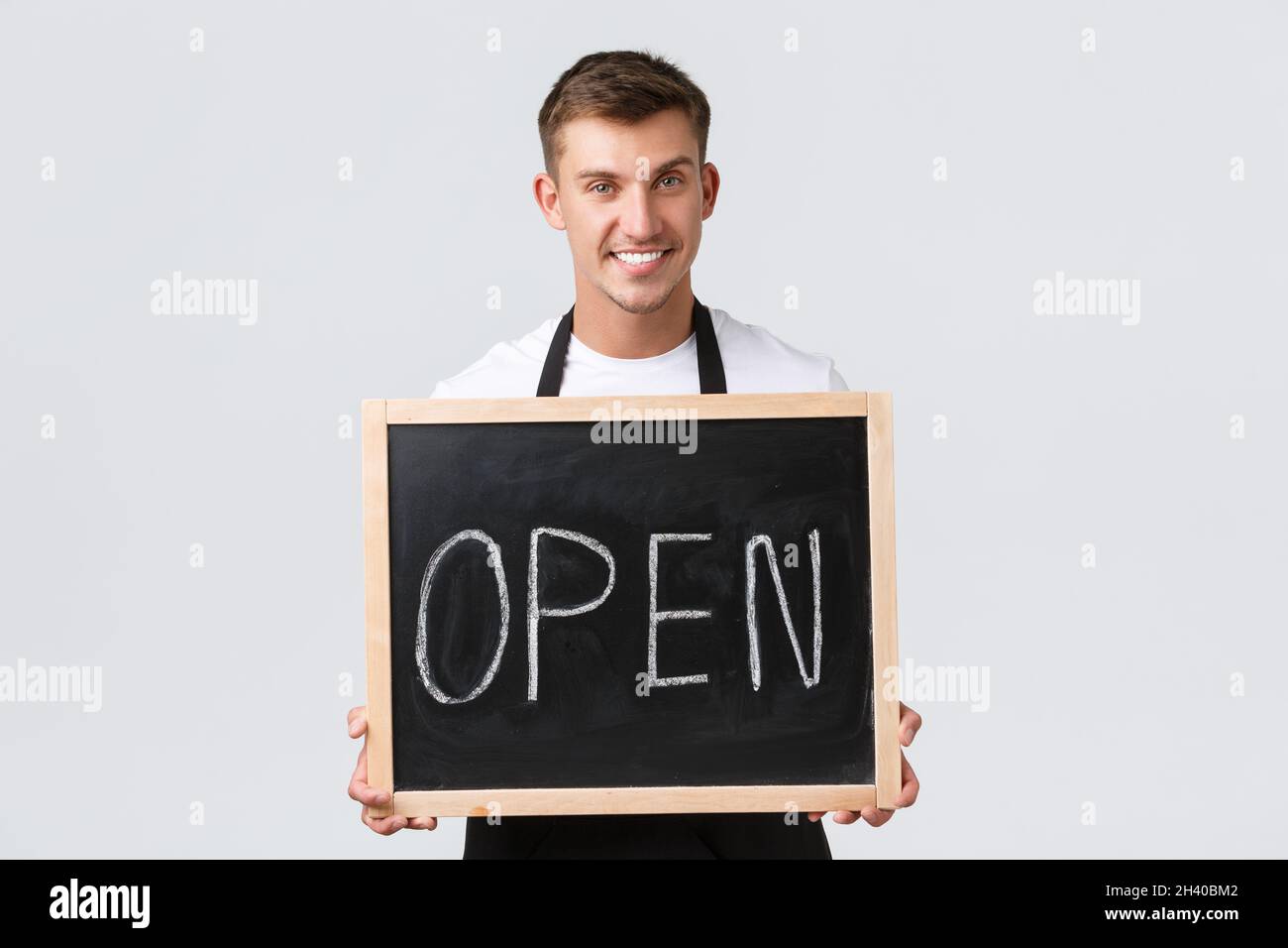 Concetto di proprietari di piccole aziende al dettaglio, dipendenti di caffè e ristoranti. Carismatico cameriere sorridente, venditore con cartello aperto, wel Foto Stock