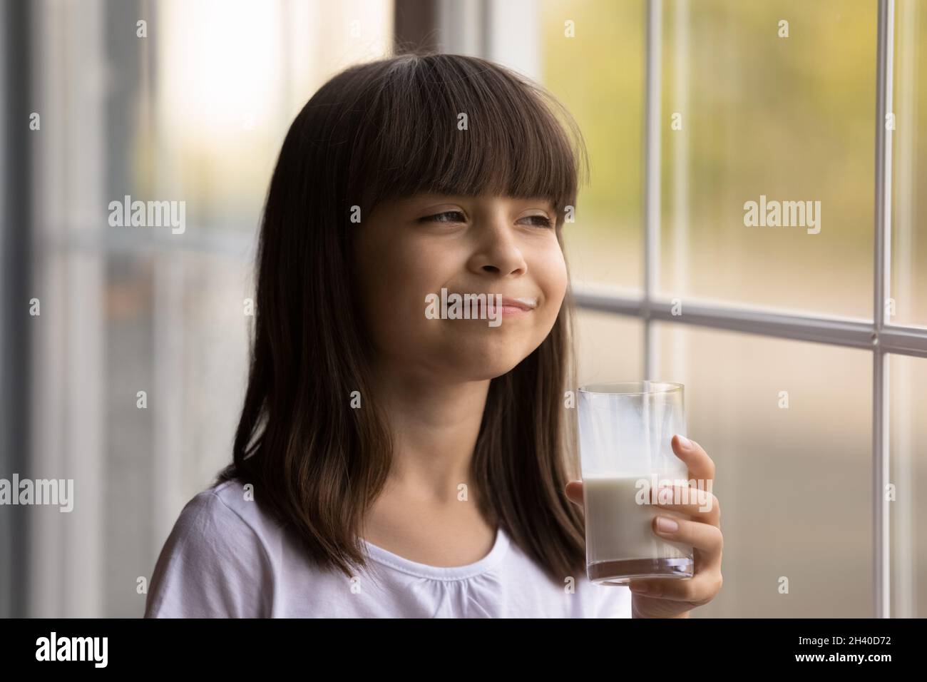 Bambino felice con baffi lattigini divertenti godendo di latte fresco sano Foto Stock