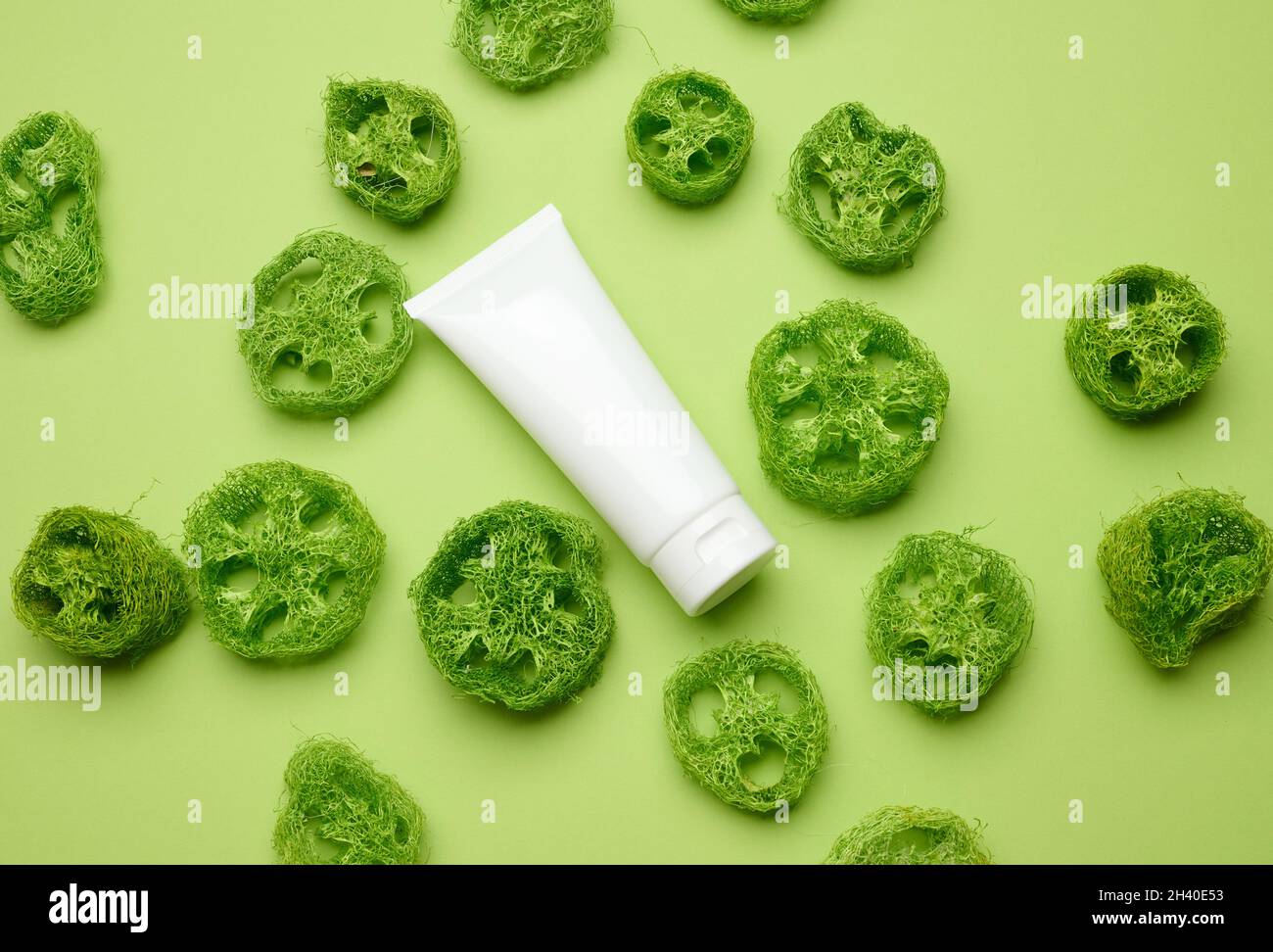 Tubi bianchi vuoti in plastica per cosmetici su sfondo verde. Confezione per crema, gel, siero, pubblicità e promozione del prodotto Foto Stock