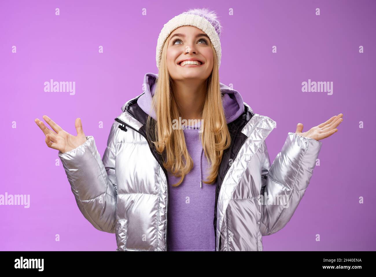 Thankful felice cute attraente giovane bionda 25s donna in inverno cappello argento trendy giacca sollevare le mani guardare in su riconoscente dio sogno c Foto Stock