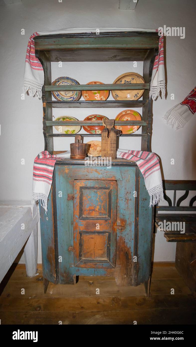 Casa contadina rumena, che illustra alcune belle lastre di argilla e contenitori di legno posti su un vecchio armadietto di legno Foto Stock