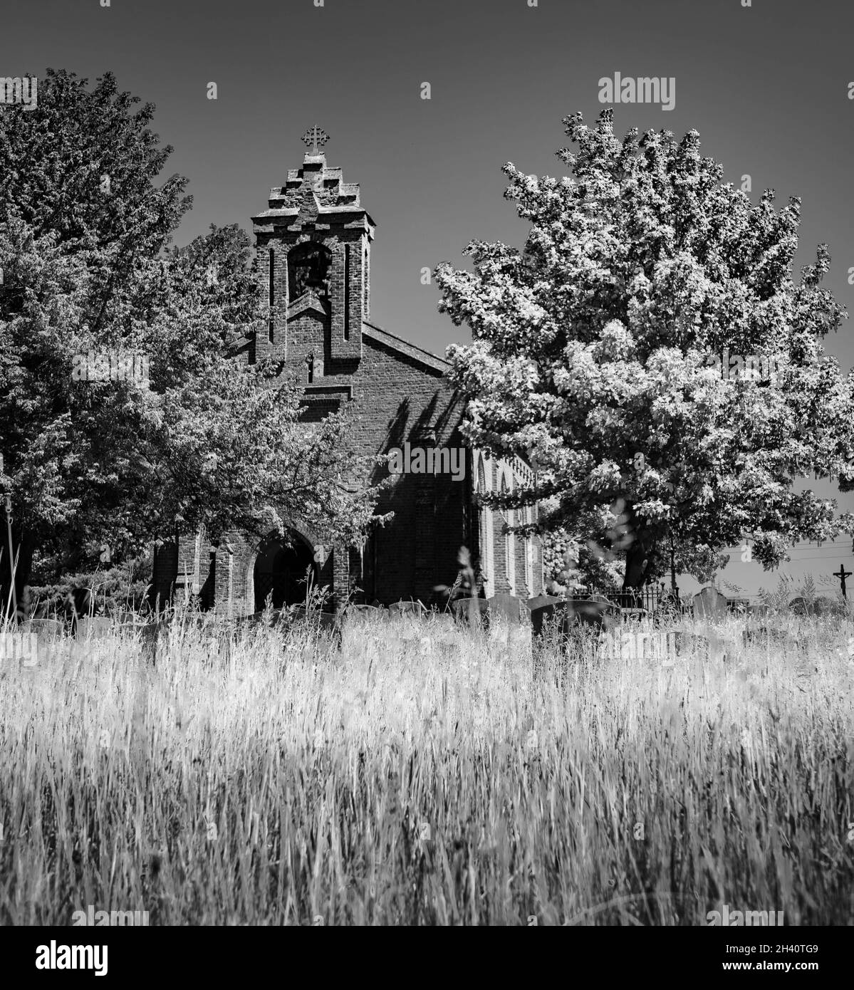Chiesa di St Margaret of Scotland esterna e cimitero con erba lunga in un giorno d'estate luminoso Foto Stock