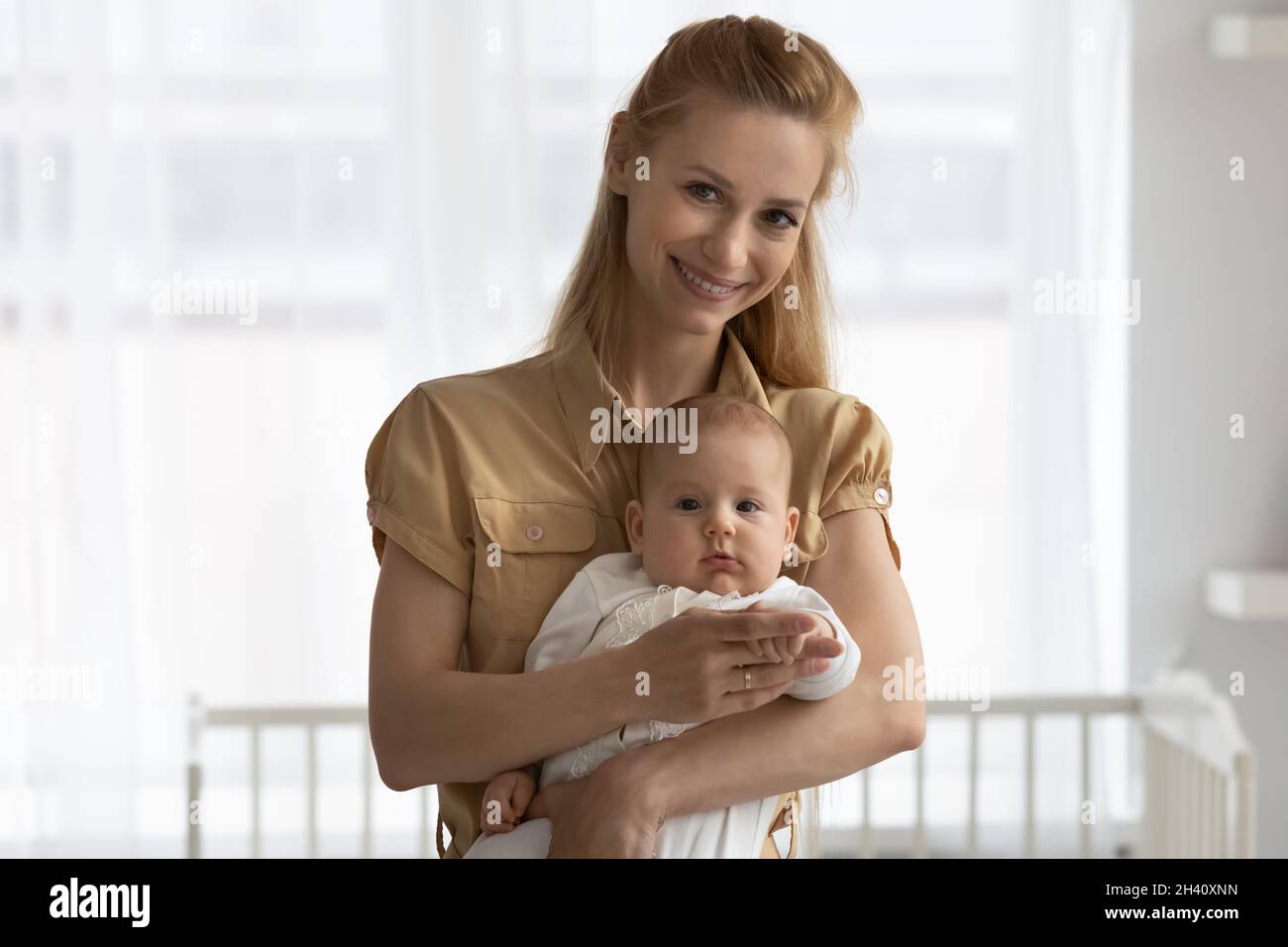 Testa ritratto di sorridente giovane madre che regge il bambino Foto Stock