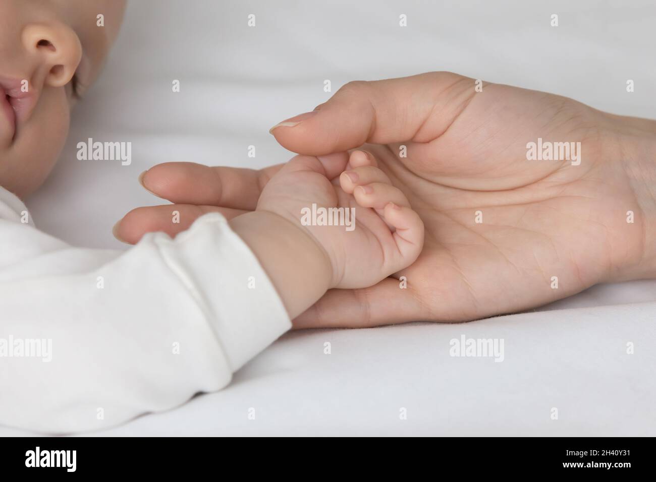 Crop close up amorevole madre toccare piccola mano del bambino Foto Stock